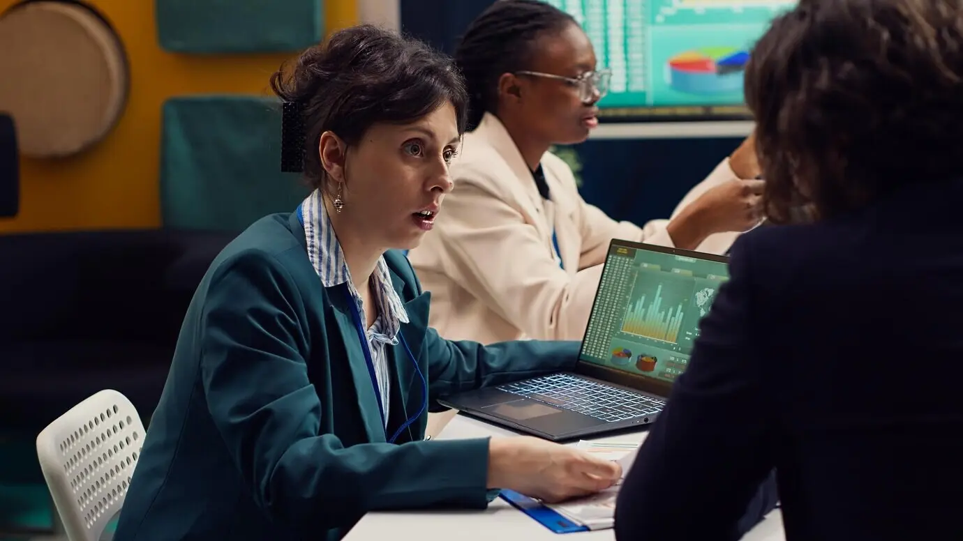 Команда стартапа просматривает финансовые отчеты и показатели эффективности на ноутбуке.